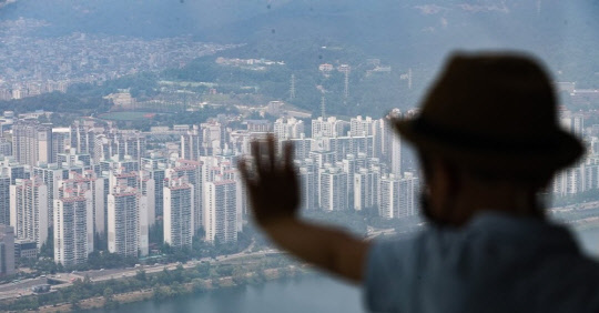 한 시민이 송파구 롯데월드타워 서울 스카이 전망대에서 아파트 밀집 지역을 바라보고 있다.<연합뉴스>